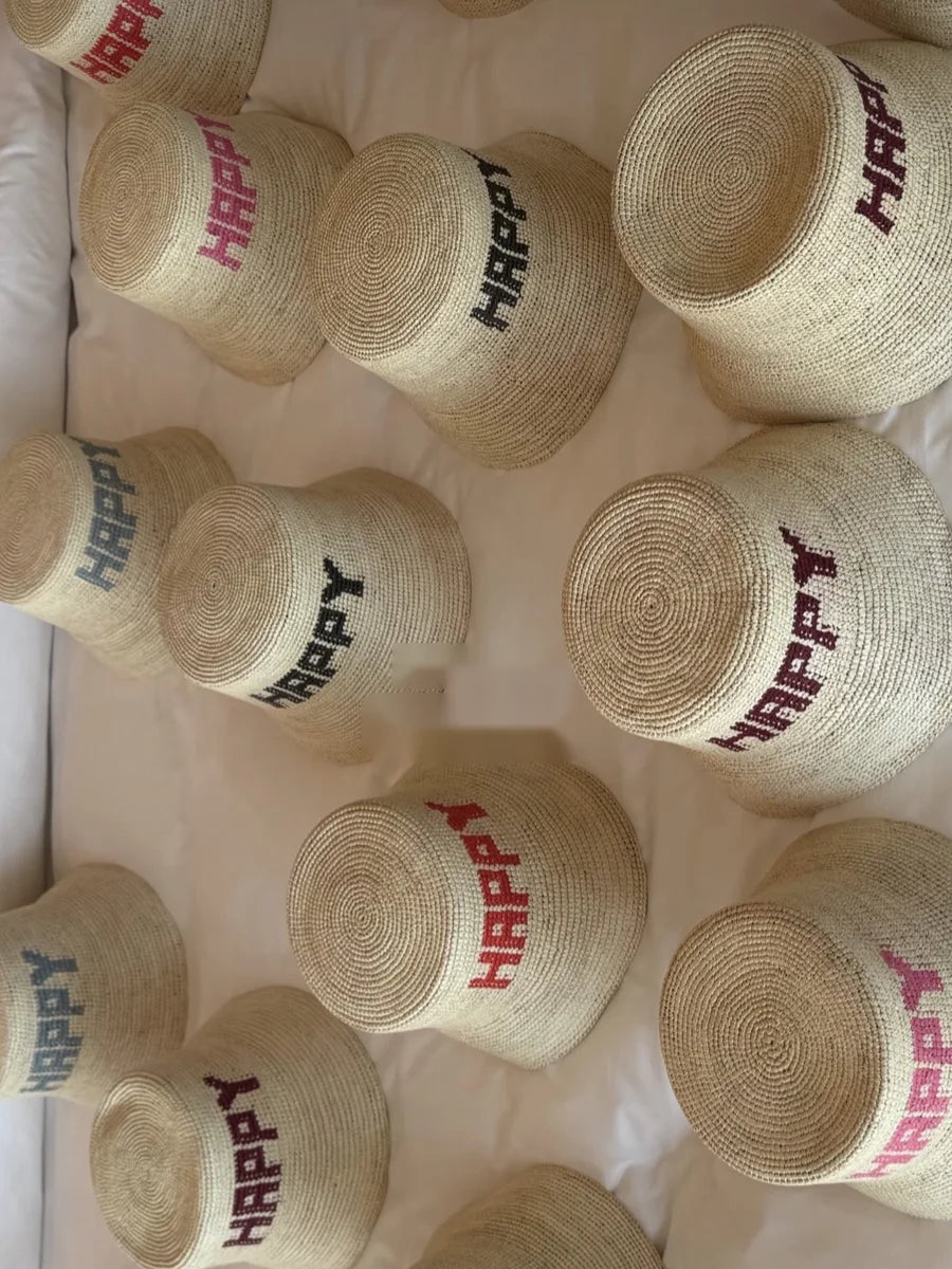 A dozen HAPPY Hats in pink, red, navy, and blue laid out for a bridal party